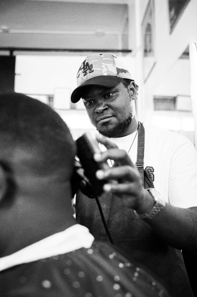 Ben Ozzly at work - professional barber cutting hair at Golden Scissors Salon, Jinja
